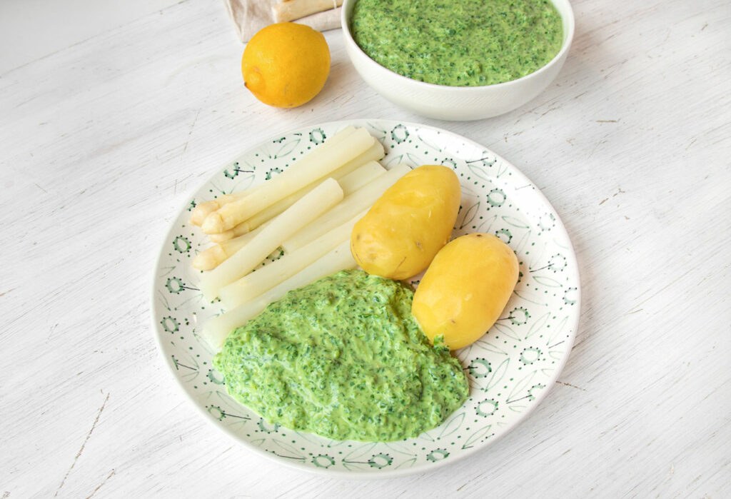 Teller mit veganer grüner Soße, Kartoffeln und weißem Spargel