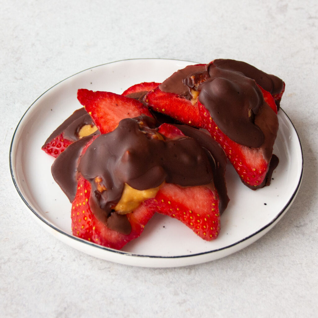 Erdbeer-Schoko-Bites gefüllt mit Erdnussmus auf einem Teller angerichtet
