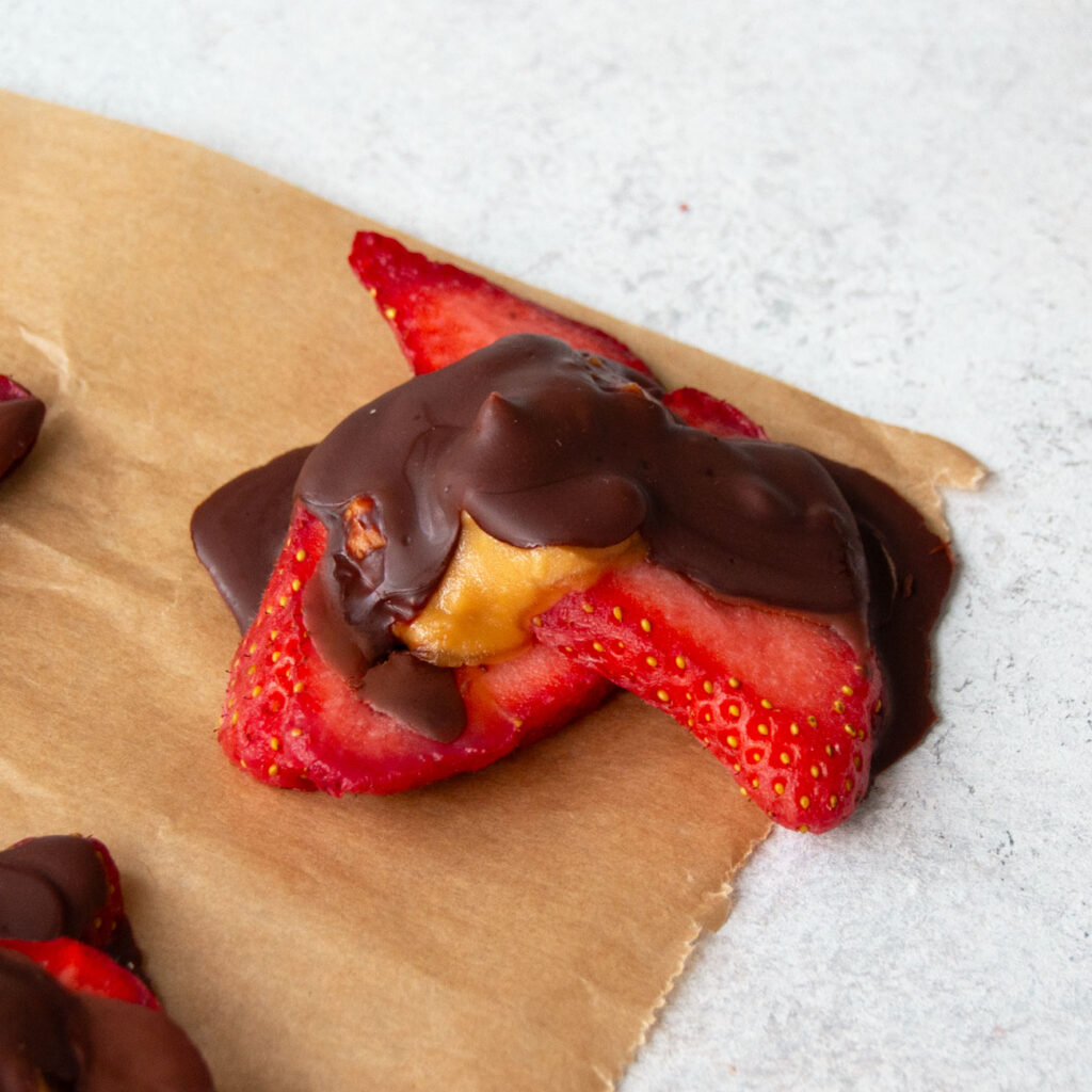 Erdbeer-Schoko-Bites gefüllt mit Erdnussmus auf Backpapier
