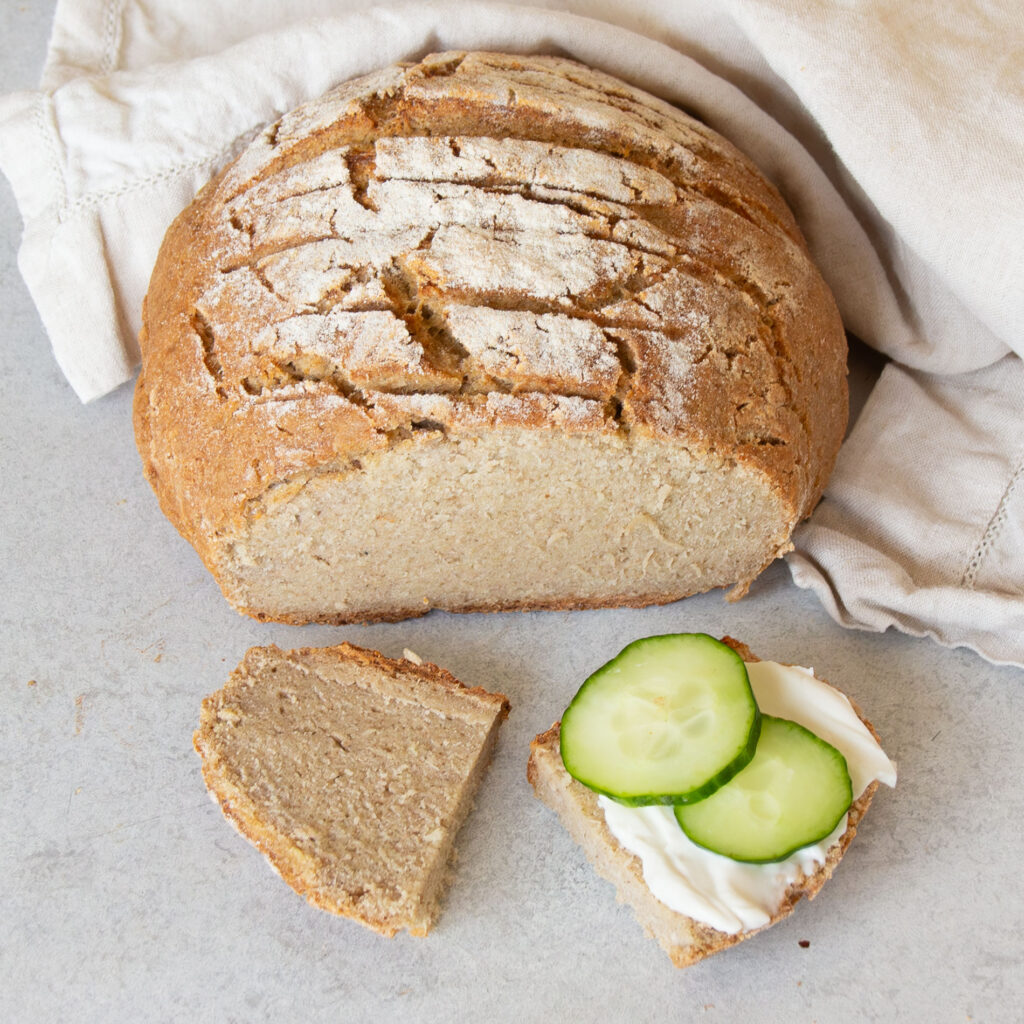 Glutenfreies Sauerteigbrot aufgeschnitten und mit Frischkäse und Gurke belegt.