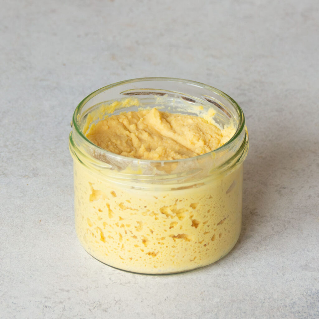 Ein offenes Glas gefüllt mit glutenfreiem Sauerteigstarter.