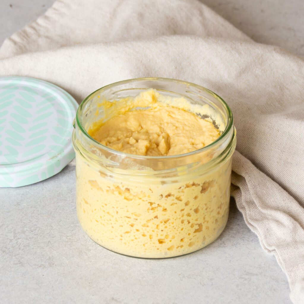 Ein Glas gefüllt mit glutenfreiem Sauerteigstarter.