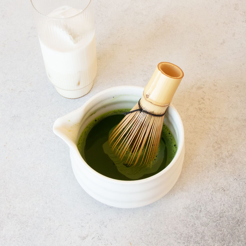 Eine Schale mit Matcha & Besen