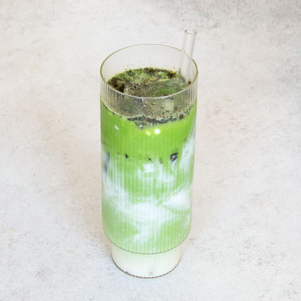 Cremiger Kokos-Vanille-Matcha in einem Glas mit Strohhalm