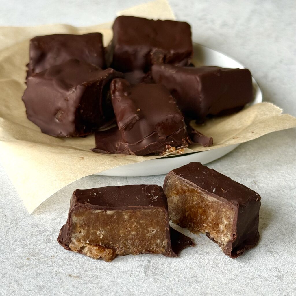 Schoko-Karamell-Bites liegen auf und vor einem Teller.