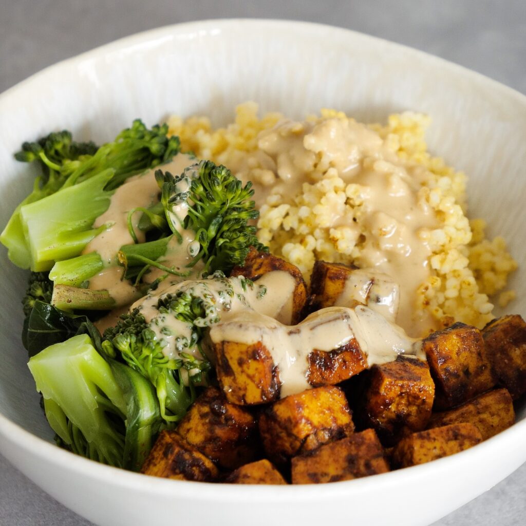 Hirse-Tofu-Bowl mit Tahini-Soße von nahem fotografiert