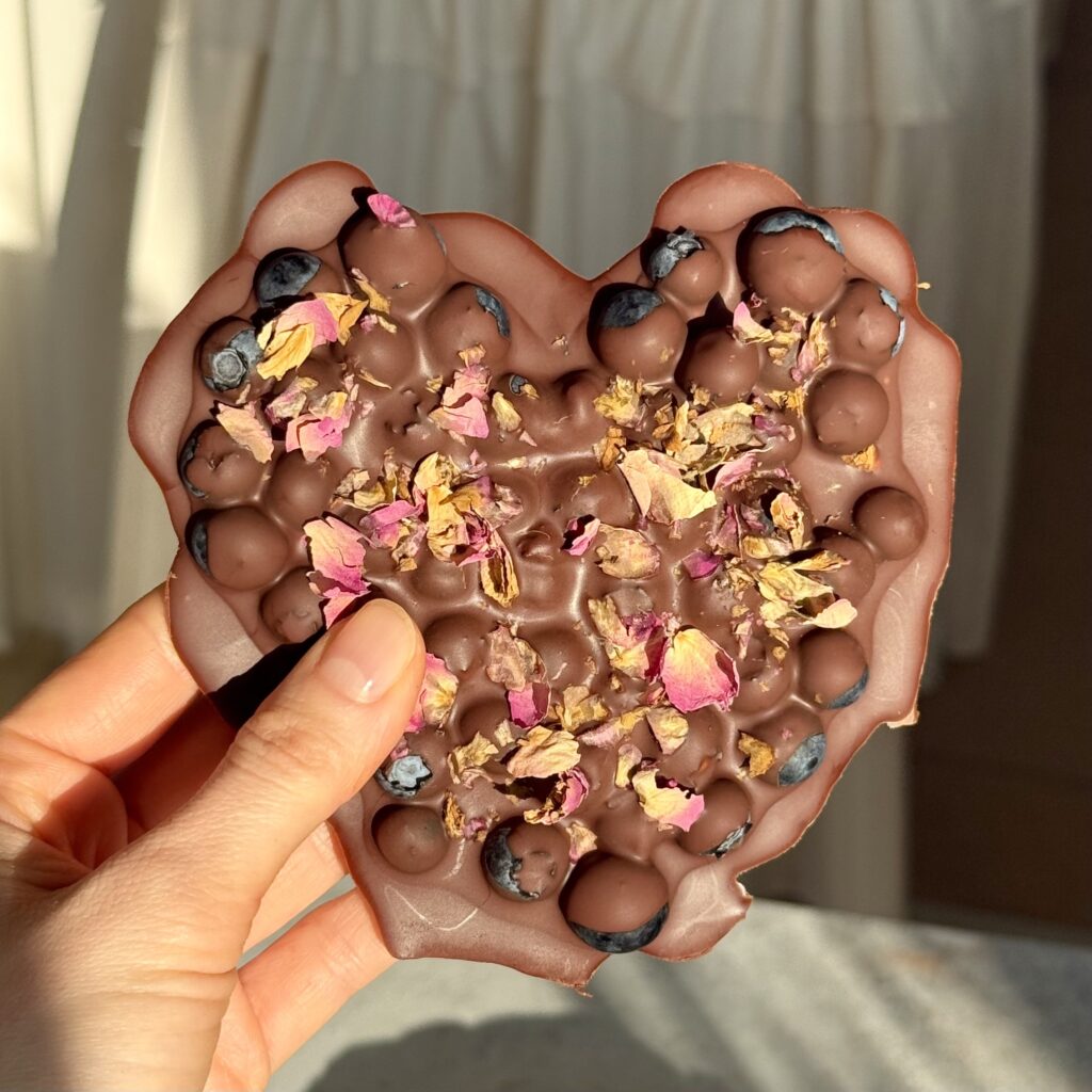 Blaubeer-Schoko-Herz wird in der Hand gehalten.