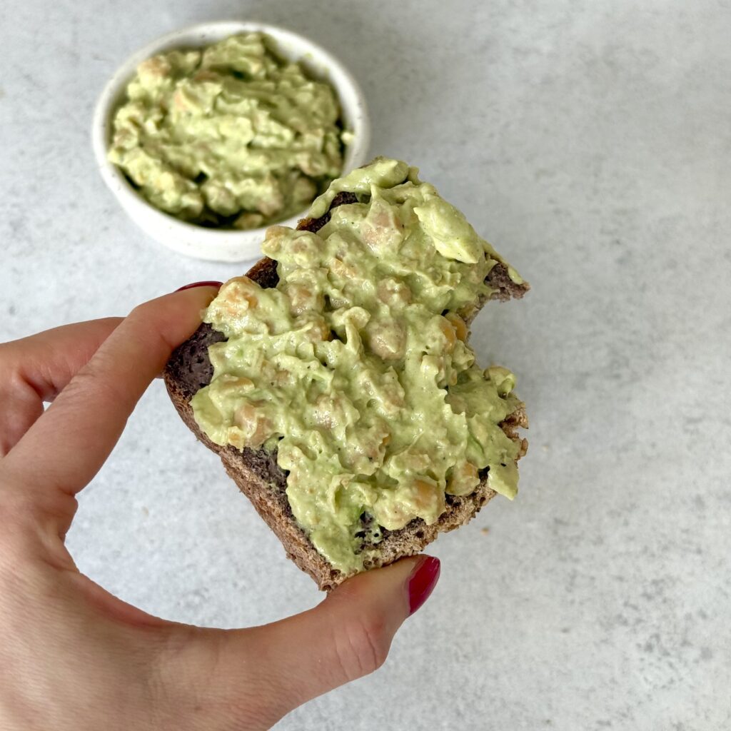 Ich halte das Kichererbsen-Mayonnaise-Sandwich in der Hand.